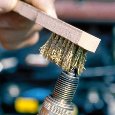 Spark plug cleaning with a metal brush