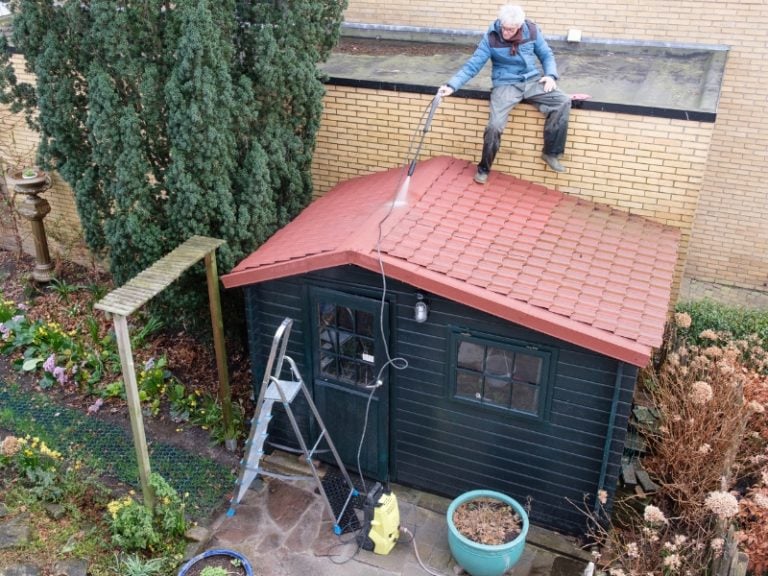 Cleaning the roof of a garden house with a pressure washer